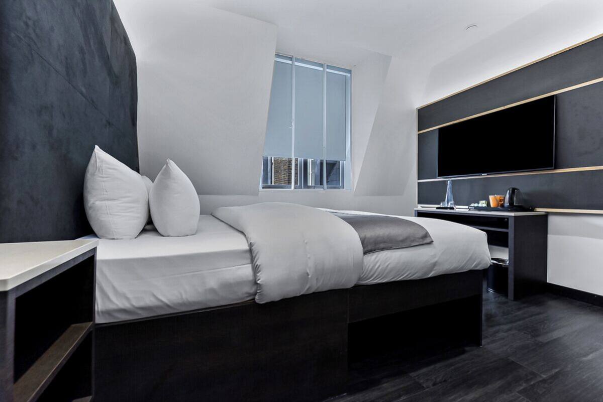 Een moderne slaapkamer met een bed, bureau en een grote televisie.