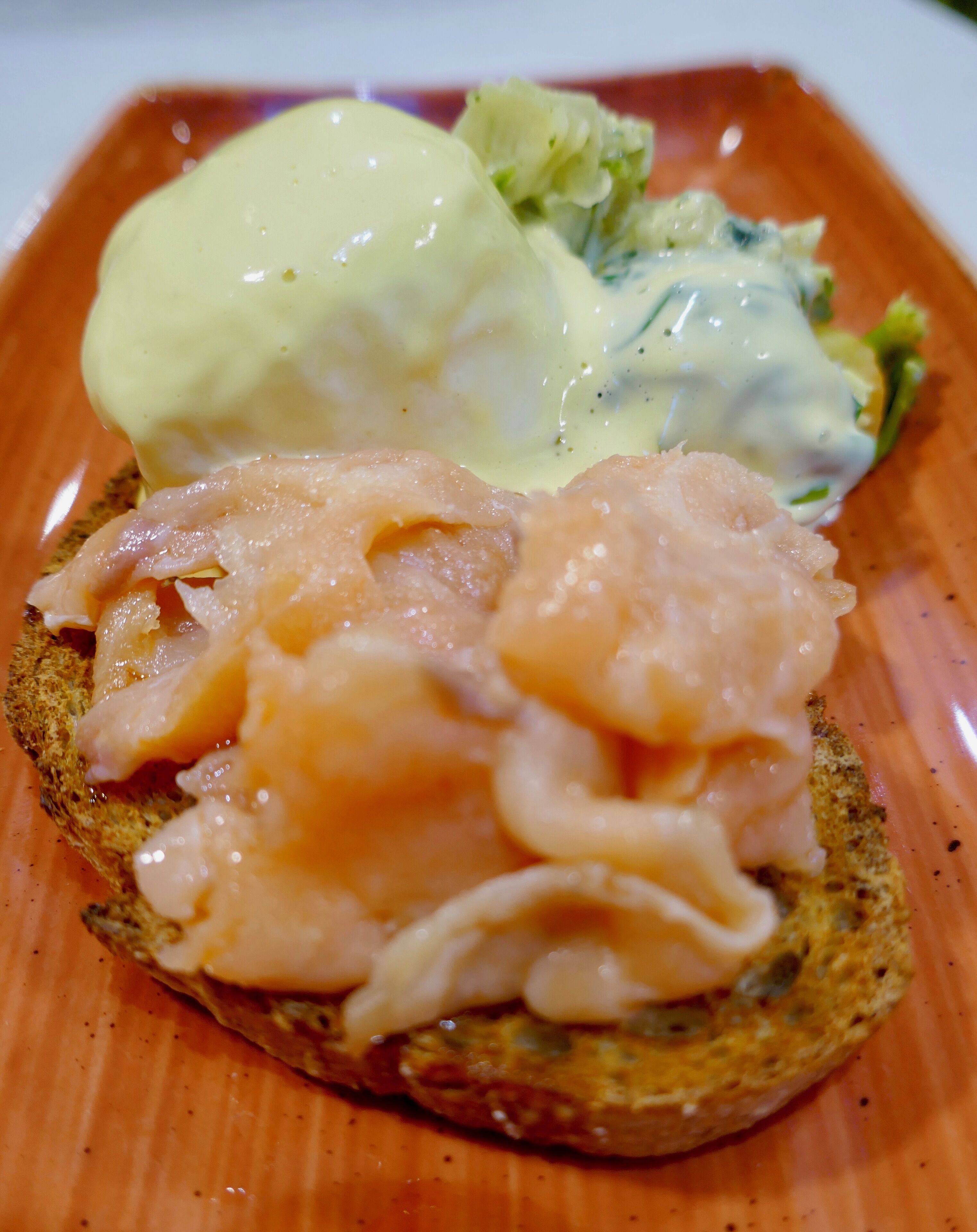 Un sándwich con salmón ahumado y salsa holandesa sobre una rebanada de pan.