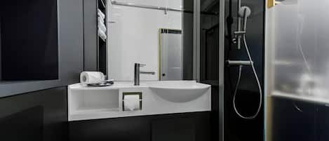 Un baño moderno con lavamanos blanco, un espejo y zona de ducha.