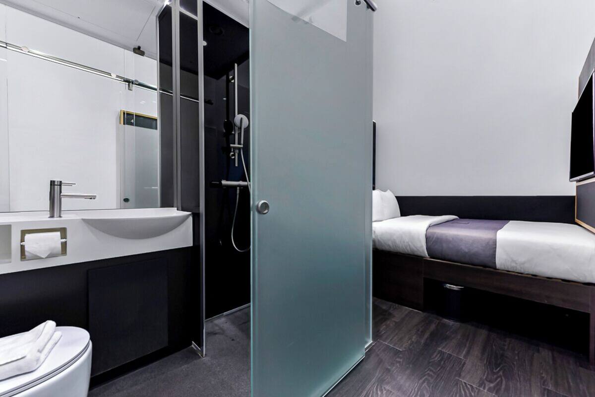 Een moderne badkamer met een douchecabine van glas, een wastafel en een toilet.