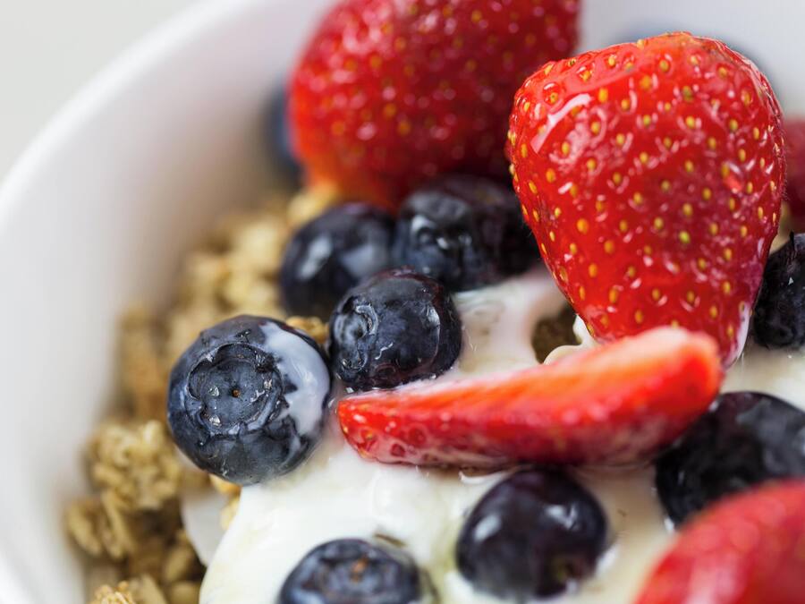 Un tazón de yogur con fresas y arándanos.