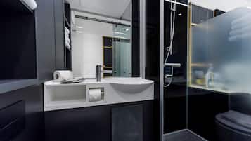 A modern bathroom with a large mirror, a white sink, and a glass shower enclosure.