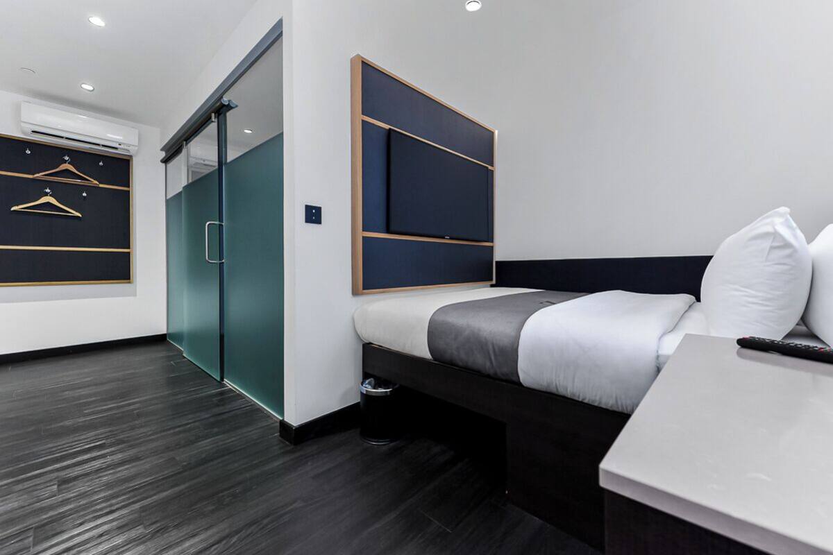 Een moderne hotelkamer met een bed, een bureau, een stoel, een kledingkast en een schuifdeur.