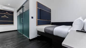 A modern hotel room with a bed, a desk, a chair, a wardrobe, and a sliding door.