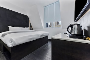 Relax in a spacious room with a large bed, desk, and city view.