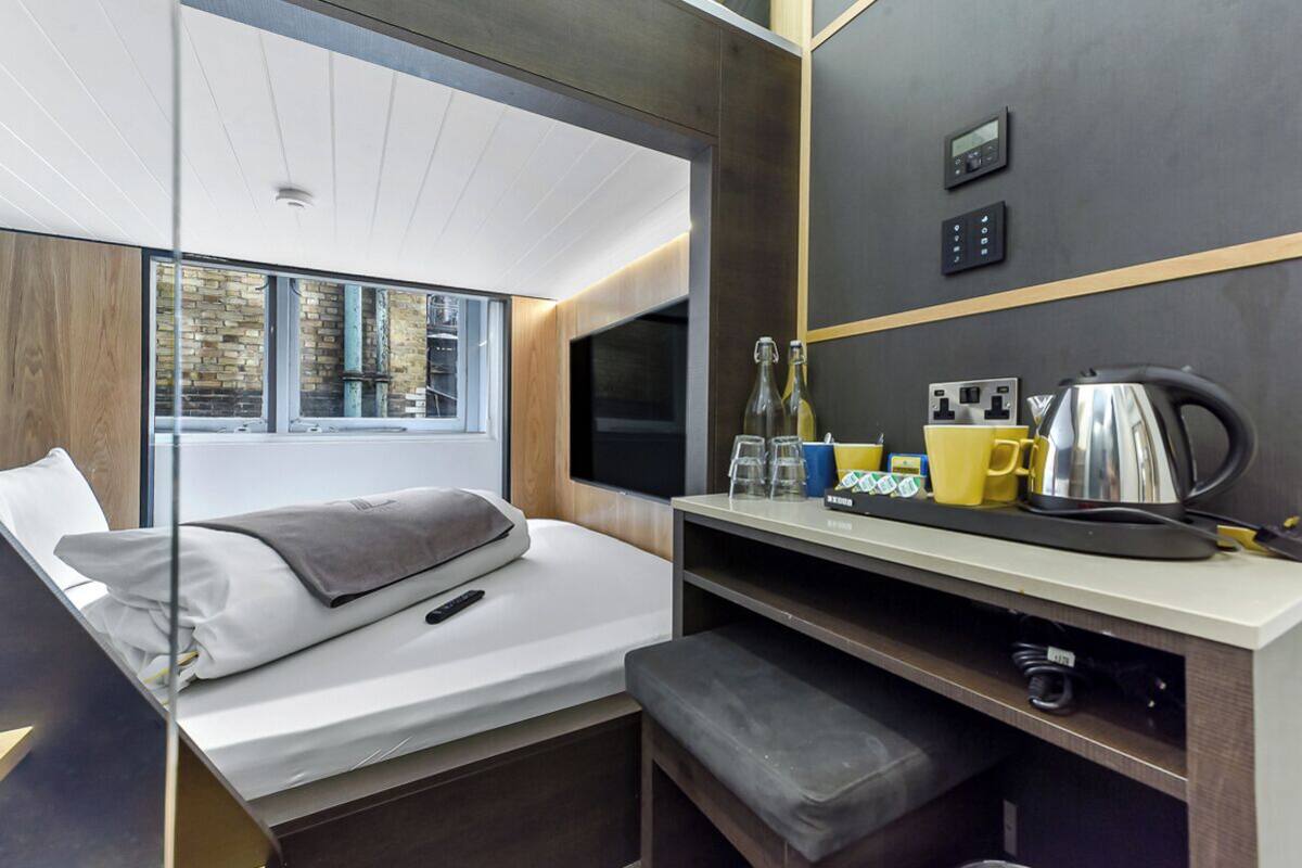 Een moderne hotelkamer met een bed, een bureau met een waterkoker, en een raam met uitzicht.