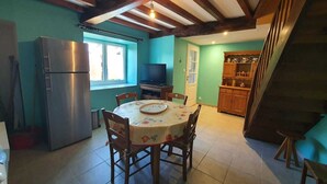 A dining area with a round table, chairs, a refrigerator, and a television. - Gite "Le Raoulet" , at the foot of the Col d'Ayens, in the hamlet of Boussan (Soulan)