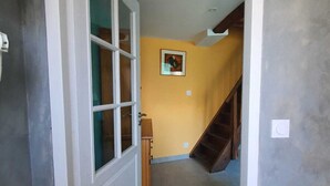 A hallway with a white door, a wooden bench, and a staircase leading to another floor. - Gite "Le Raoulet" , at the foot of the Col d'Ayens, in the hamlet of Boussan (Soulan)