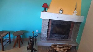 A cozy room with a fireplace, a small table, and a chair. - Gite "Le Raoulet" , at the foot of the Col d'Ayens, in the hamlet of Boussan (Soulan)
