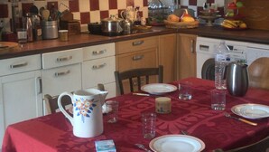 Een keuken met een eettafel voor vier personen, voorzien van eenvoudig servies en een rode tafelkleed.