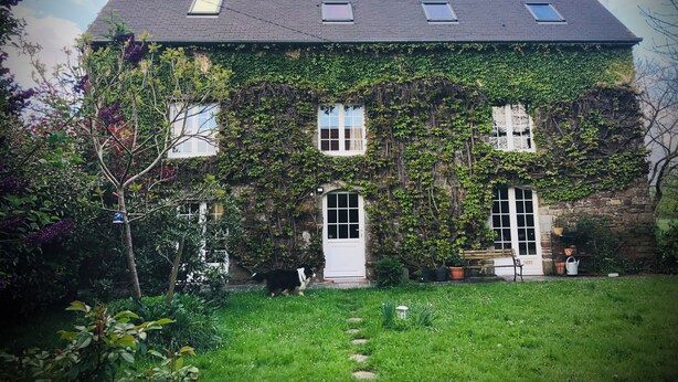 Een stenen huis met muurranken, een schuin dak en een kleine tuin.