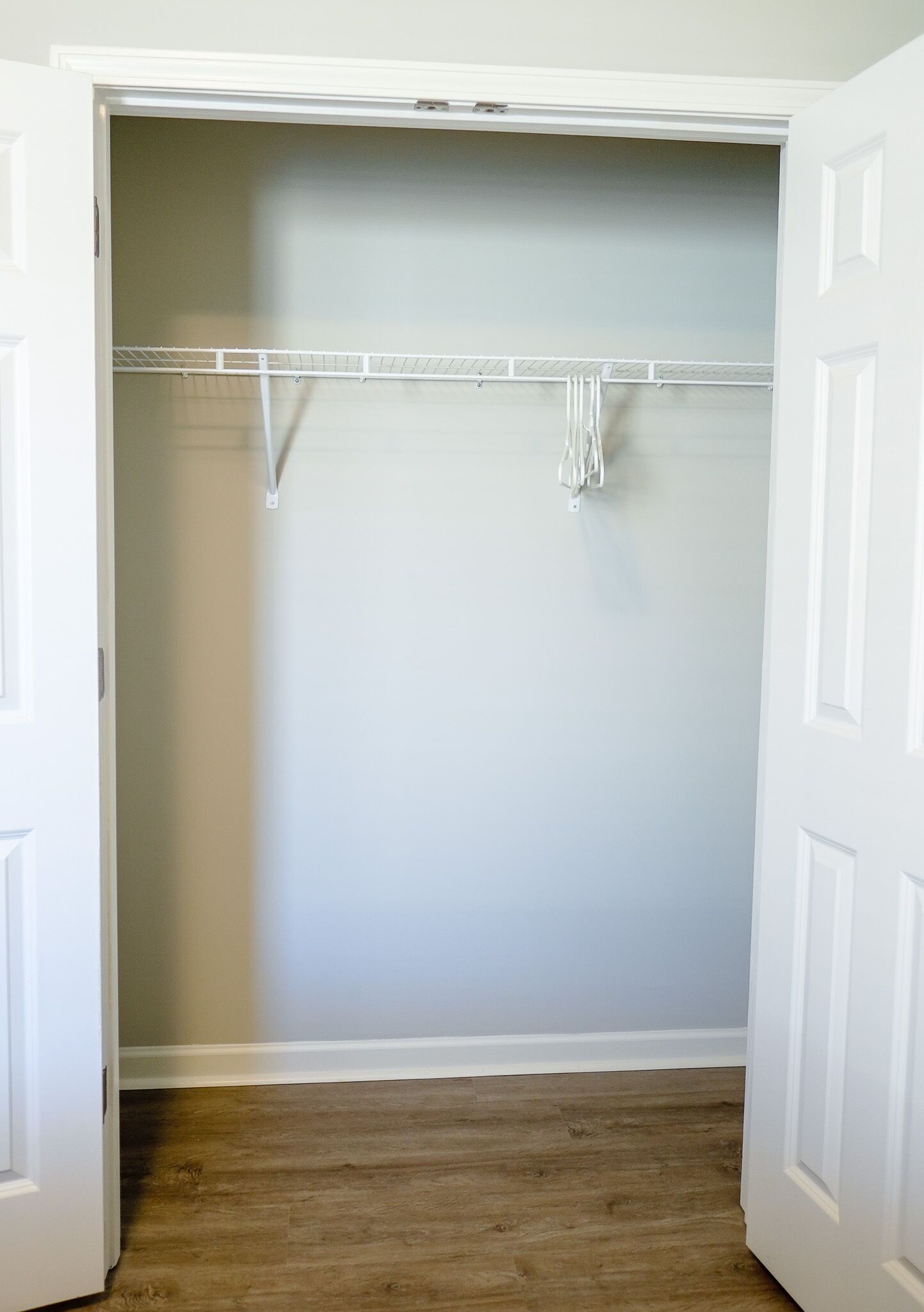 A walk-in closet with a wooden floor and white walls.