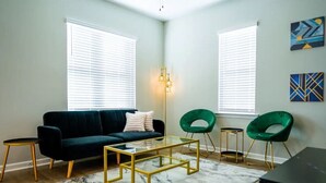 A modern living room with a dark green sofa, a glass coffee table, and two green chairs. - Stylish and NEW! Duke~Art Deco (Durham)