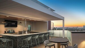 A rooftop bar with a bar counter, seating area, and a large TV screen. - SpringHill Suites by Marriott Tampa Downtown (Tampa)
