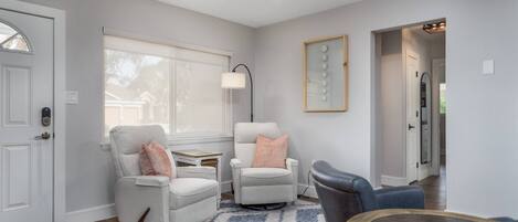 A living room with two armchairs, a coffee table, a lamp, and a large window.