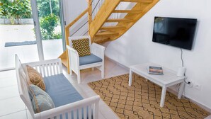 A modern living room with a staircase, a sofa, a coffee table, and a TV. - La Villa Armony (Lamentin)