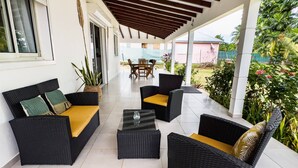 A covered outdoor seating area with wicker furniture and a tiled floor. - La Villa Armony (Lamentin)