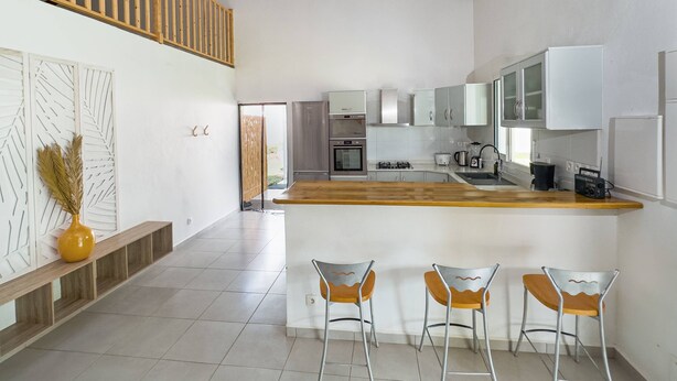 A spacious kitchen with a wooden island, bar stools, and modern appliances. - La Villa Armony (Lamentin)