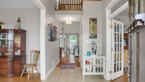 A hallway with a wooden staircase, a white cabinet, and a chair. - Top of Lemont - Minutes to Downtown State College and Penn State (Lemont)