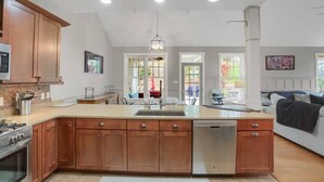 A modern kitchen with wooden cabinets, a central island, and a dishwasher. - Top of Lemont - Minutes to Downtown State College and Penn State (Lemont)