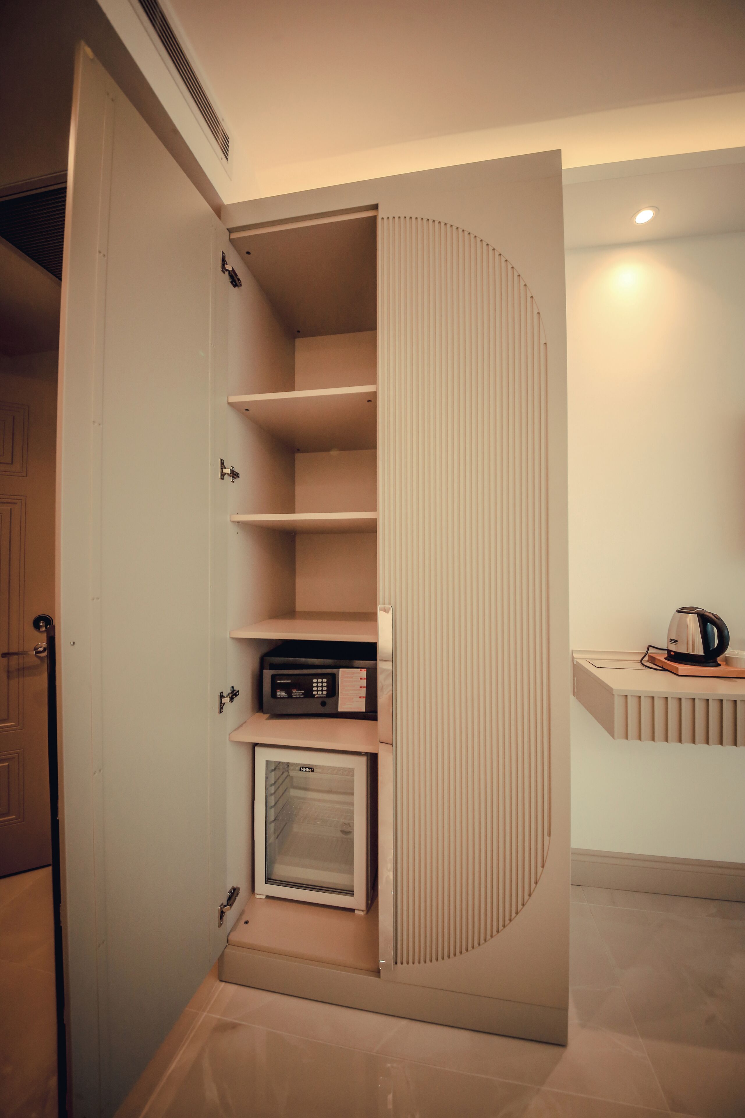 A compact kitchen with a built-in microwave, a small refrigerator, and a coffee maker on the countertop.