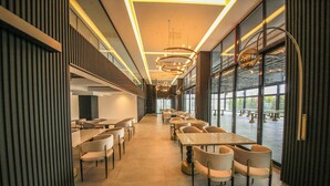 A modern dining area with long tables and chairs, large windows, and contemporary lighting fixtures. - GÖRGÜLÜ HOTEL (Kesan)