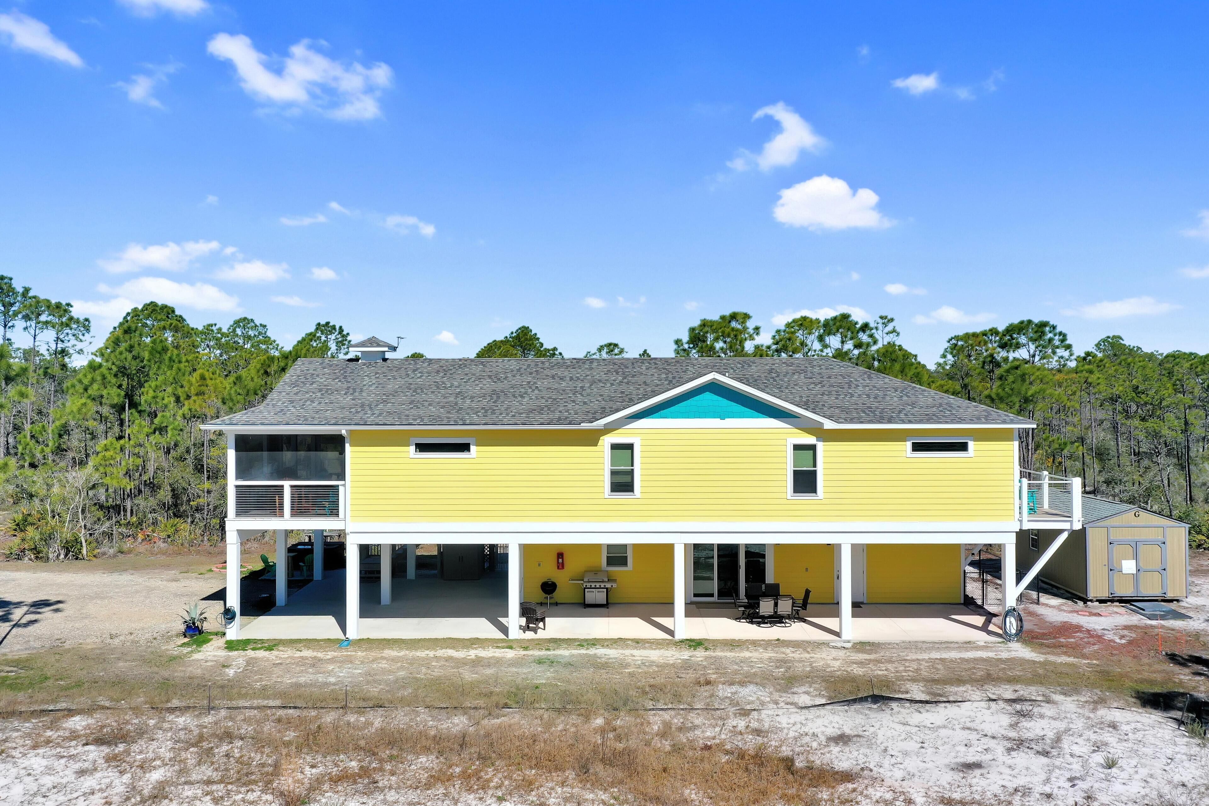 A two-story yellow house with a covered porch, a small garage, and a fenced yard.