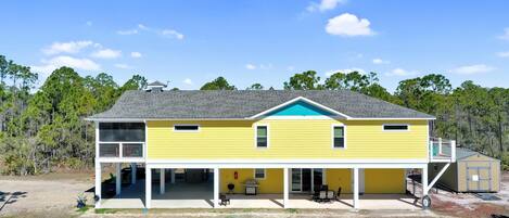 A two-story yellow house with a covered porch, a small garage, and a fenced yard.