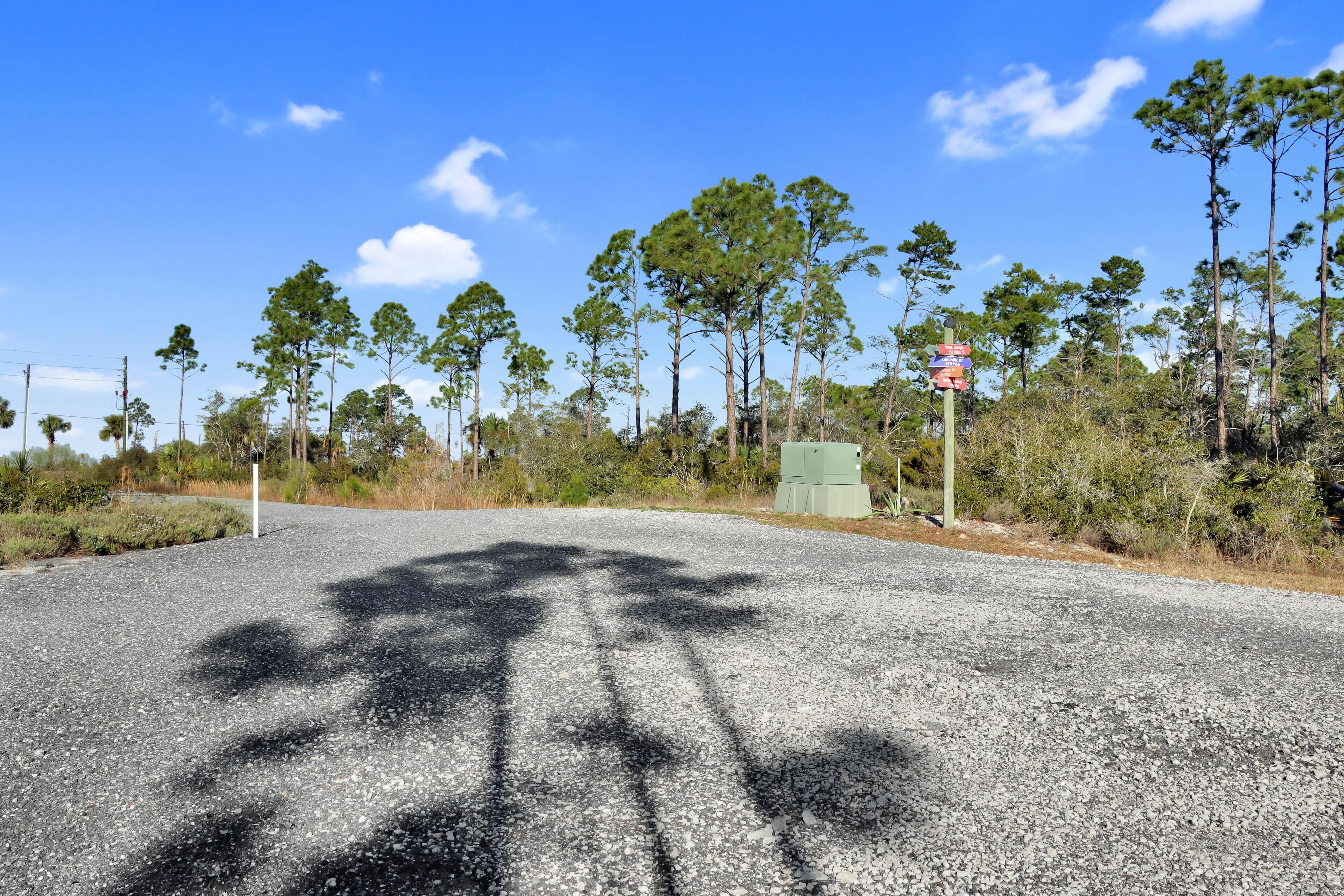 A road with a signpost and trees in the background.