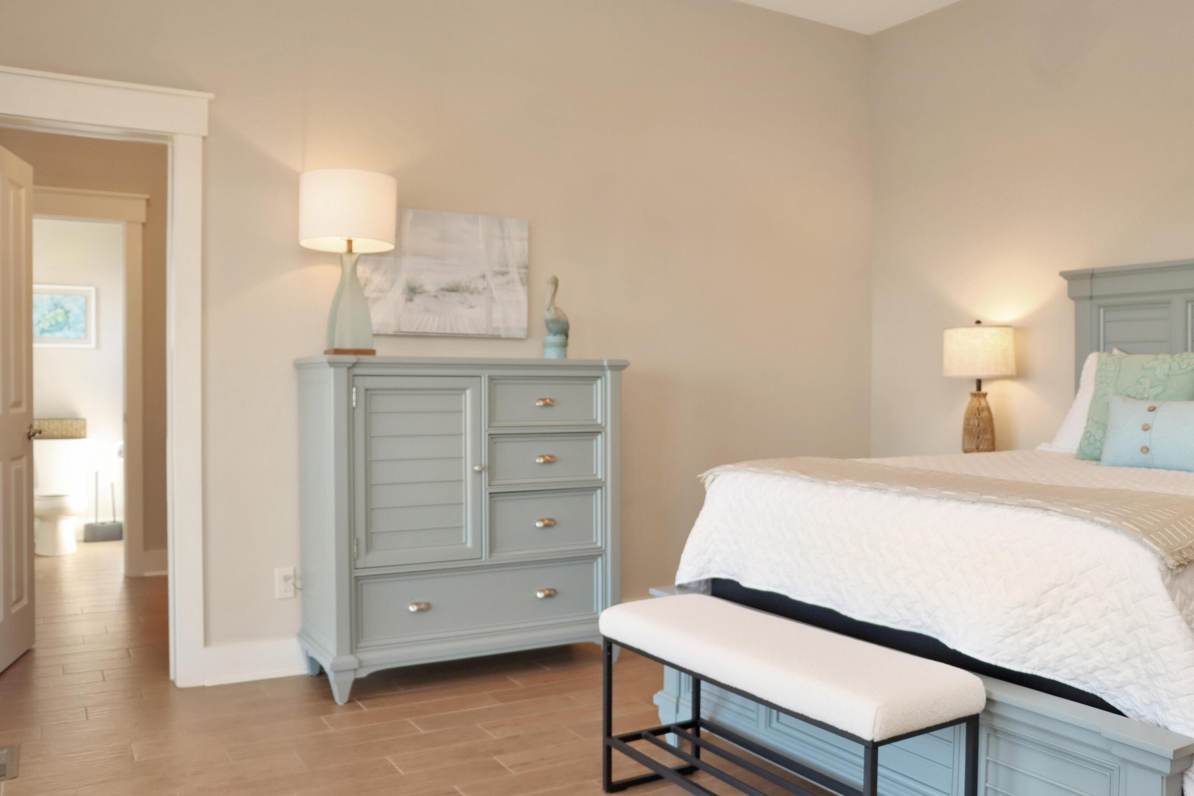 A bedroom with a bed, a bench, a dresser, and two lamps.