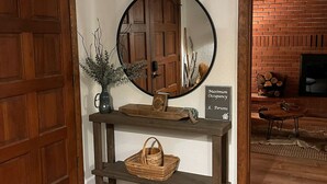 Une porte en bois, un miroir, une enseigne, une console, un panier et un tapis à motifs.