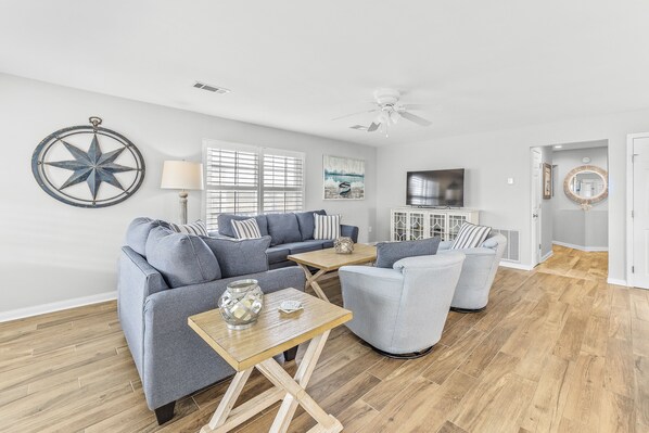 A modern living room with grey sofas, a wooden coffee table, and a ceiling fan. - 50 Steps to the Beach with Ocean View ~ Beach Gear (Gulf Shores)