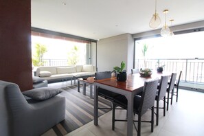 A modern living room with a dining area, featuring a sofa, a dining table with chairs, and a large window with a view of the outdoors. - Bento 101 in S o Paulo (São Paulo)