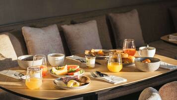 Una mesa de madera con un desayuno preparado, varios alimentos, bebidas y una taza.