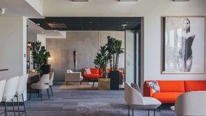 Un hall d’hôtel moderne comprenant un espace salon, un comptoir d’accueil et une grande œuvre d’art encadrée au mur.