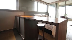 A modern hotel room with a wooden desk and bar stool, large windows, and a bed with white bedding. - Melo 1701 in S o Paulo (São Paulo)