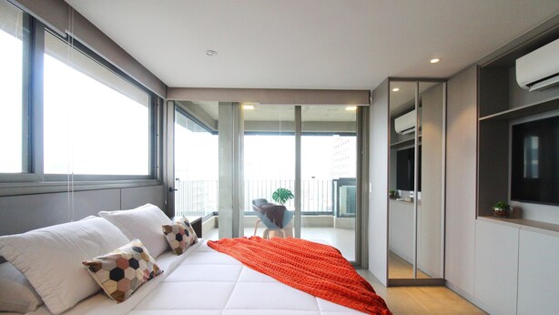 A modern hotel room with a large bed, a balcony with a view, and a TV mounted on the wall. - Melo 1701 in S o Paulo (São Paulo)