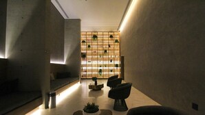 A modern lobby with a minimalist design, featuring a seating area with sofas and a coffee table, a wall-mounted plant display, and a clean, tiled floor. - Melo 1701 in S o Paulo (São Paulo)