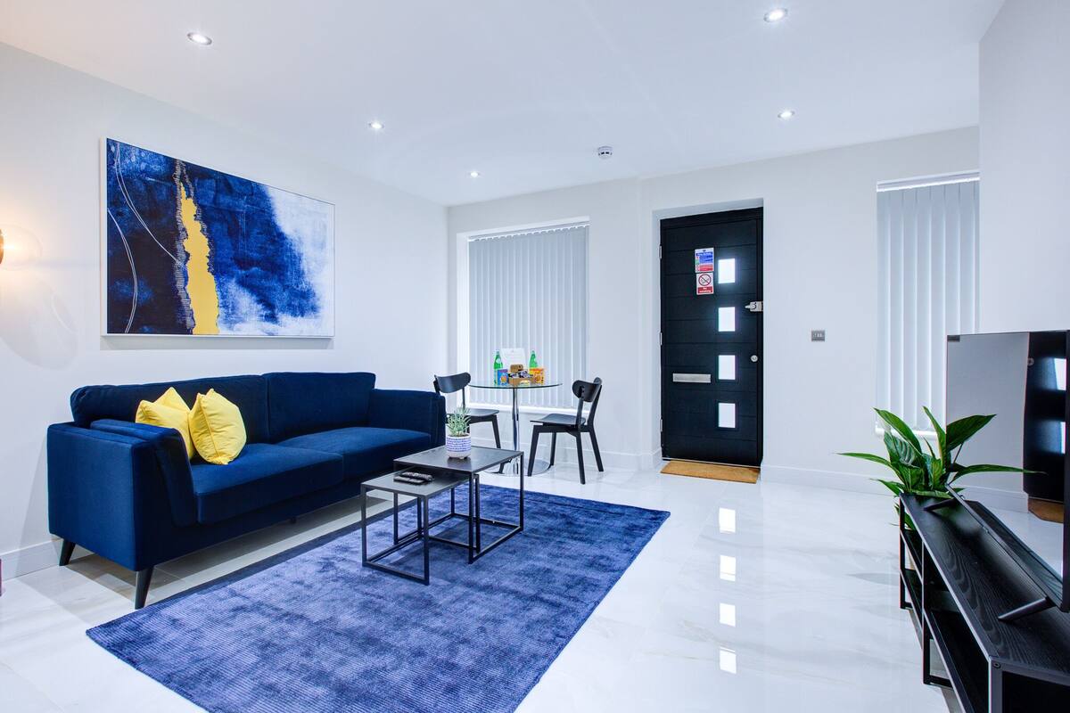 Uma sala de estar moderna com um sofá azul, uma mesa de centro e uma grande pintura abstrata.