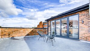 A rooftop terrace with two metal chairs, a glass door leading inside, and a brick wall. - Hybrid Resi - Uxbridge  (Uxbridge)