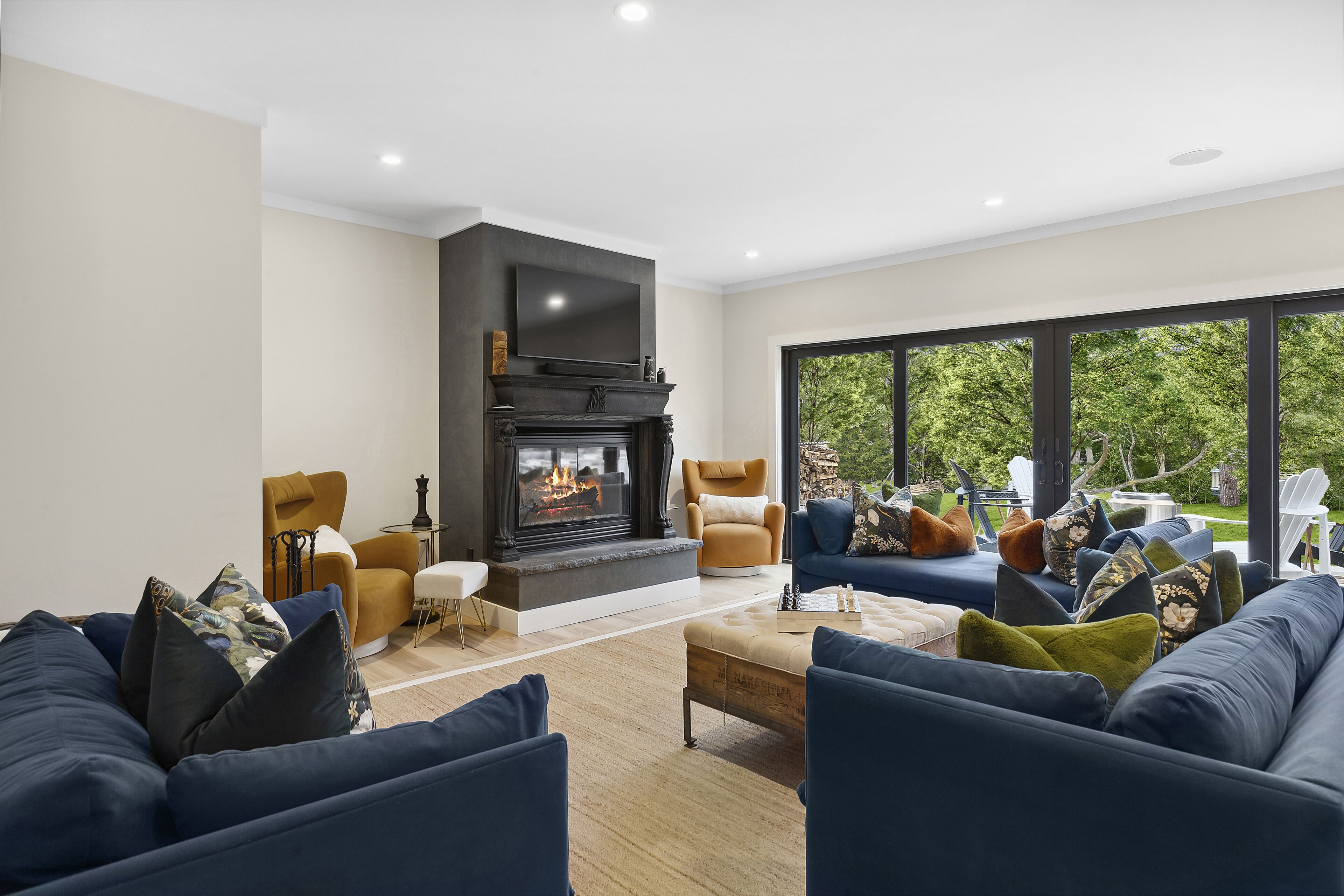 Una sala de estar moderna con chimenea, asientos cómodos y ventanas amplias que ofrecen vistas al exterior.