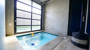 Ein kleiner, überdachter Pool mit einem gelben Quietscheentchen, einem Korbwannen und einem großen Fenster mit Jalousien.