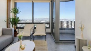 Un salon moderne avec un balcon, de grandes fenêtres, un canapé, une table basse et une plante en pot.