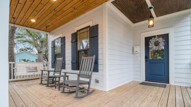 A porch with wooden flooring and a bench.