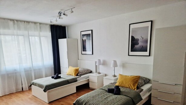 Une chambre d’hôtel avec deux lits simples, une armoire, un bureau et une chaise.