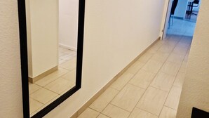 Un couloir doté d’un grand miroir, de murs aux couleurs claires et d’un sol carrelé.