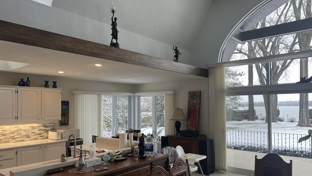 A spacious kitchen with a large island, white cabinetry, and a view of a snowy landscape through large windows.