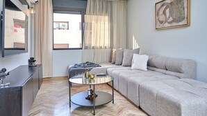 Una sala de estar moderna con un sofá, una mesa de centro y un televisor sobre un mueble.