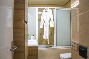 A bathroom with a bathtub, a toilet, and a robe hanging on the wall.