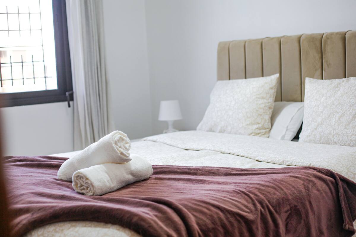 A neatly made bed with a brown blanket, white pillows, and a headboard.